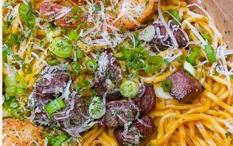Garlic noodles topped with shrimp, diced steak, parmesan and green onion